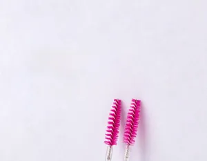 Macro detail of disposable mascara wand with pink spiral bristles and clear crystal handle