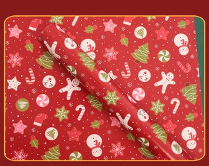 Close-up of red Christmas wrapping paper featuring gingerbread men, snowmen, and elk motifs