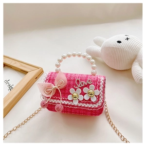 Detail of pink tweed girl's handbag with pearl handle, bow, and gold chain strap