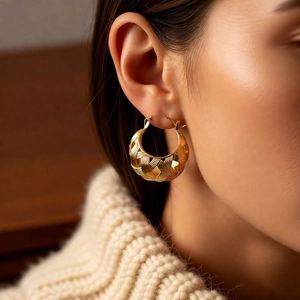 Close-up of 18k gold plated hollow U-shape hoop earring with woven texture on ear