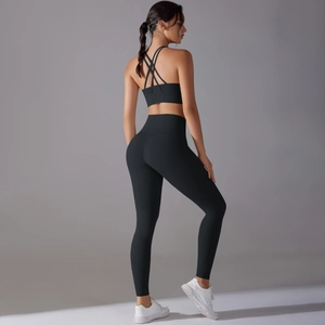 Detail of cross-back sports bra and high-waisted leggings in black athletic fabric