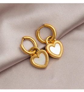 Detailed close-up of golden heart earrings with white mother-of-pearl inlay on silk background
