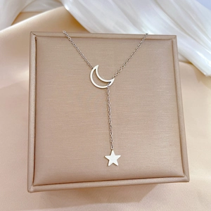 Macro shot of silver crescent moon and star pendants on a titanium steel necklace