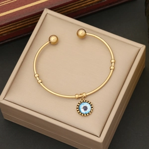 Dettaglio del bracciale in acciaio dorato con pendente malocchio su cuscino portagioie