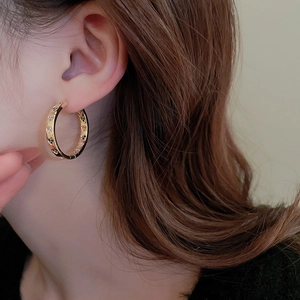 Close-up of gold twisted hoop earrings with multi-colored cubic zirconia on female model