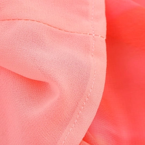Close-up of lightweight coral pink chiffon fabric texture and high-quality stitching detail