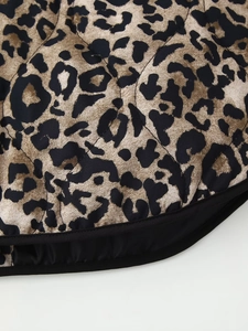 Macro view of leopard print quilted fabric with black piping detail on winter jacket