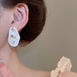 Gros plan de boucles d'oreilles fleur en nacre avec cristaux et rose dorée sur un mannequin