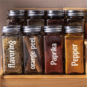 Square glass spice jars with metal lids organized neatly on a wooden tiered rack