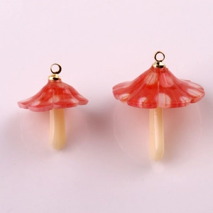 Macro detail of red spotted acrylic mushroom charms with gold loops for DIY jewelry