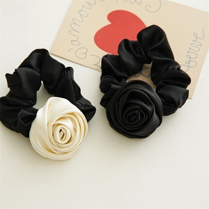 Close-up of handmade satin rose scrunchies in cream and black colors with elegant silk texture