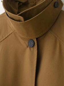Detail of camel trench coat collar with twill texture and black button fastening