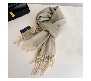 Close-up of a 100% wool light green scarf with orange stripes and tassel details