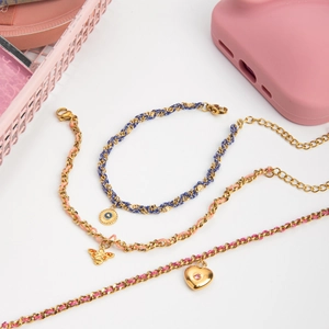 Détail de bracelets en acier inoxydable doré 18K avec breloques cœur rose et abeille