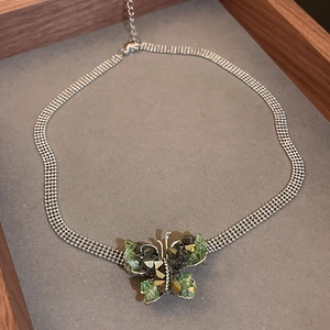 Detailed view of silver mesh chain necklace with green and black crystal butterfly pendant