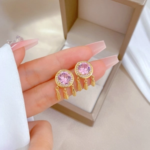 Detailed shot of dreamcatcher earrings with pink stone and golden feather tassels