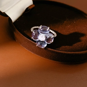 Détail de la bague trèfle aux pierres mauves et anneau torsadé sur boîte à bijoux