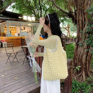 Outdoor lifestyle shot of a yellow bubble texture tote bag on a cafe terrace