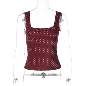 Dettaglio ravvicinato del crop top senza maniche rosso vino a pois bianchi con scollo a U