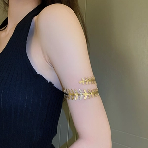 Detailed macro shot of a golden leaf-shaped upper arm cuff with intricate vine textures