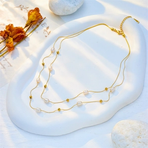 Collier double rang doré avec perles blanches et billes d'or sur support nuage blanc