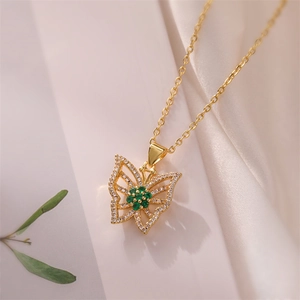 Close-up of gold butterfly necklace with green gemstone and sparkling crystals detail