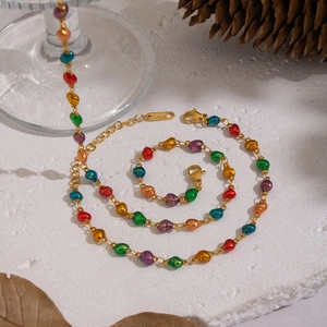 Detail of a gold-plated shell necklace with vibrant colorful beads on a white stone base