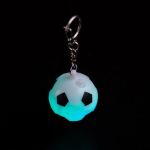 Macro view of a luminous soccer keychain with ice blue LED light and silver metal chain