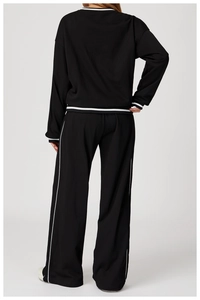 Back view of a black knit tracksuit with contrasting white stripe details and wide leg pants