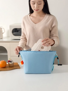 Detail of placing a bento box into the insulated light blue lunch bag with aluminum foil lining