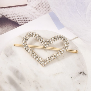 Detail shot of heart-shaped hair clip with sparkling rhinestones on golden metal base