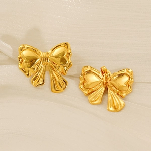 Détails de boucles d'oreilles papillon dorées sur un fond de soie beige élégant