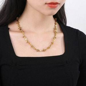 Close-up of gold titanium steel knotted coffee bean chain necklace on female model neck