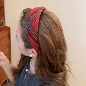 Primo piano di un cerchietto in tessuto scozzese rosso indossato da una modella