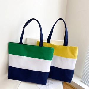 Detailed view of color block canvas tote bags in green and yellow stripe patterns