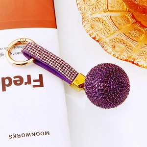 Close-up of purple rhinestone ball keychain with matching studded strap and gold hardware