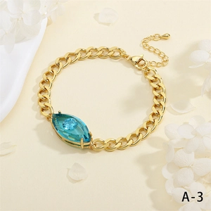 Detailaufnahme eines goldenen Panzerarmbands mit blauem Marquise-Kristall und Karabinerverschluss