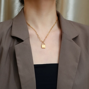 Close-up of gold stainless steel heart lock pendant on paperclip chain necklace