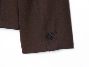 Close-up of brown blazer cuff featuring twill texture and a black round button detail