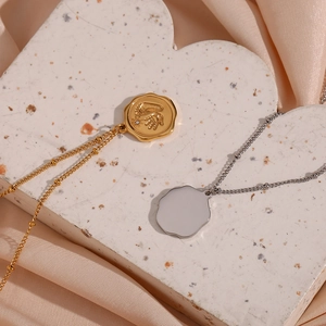 Détail du pendentif doré empreintes de nouveau-né sur surface marbre et tissu en soie