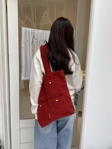 Detail view of red felt tote bag with three front pockets and colorful dotted buttons