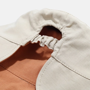 Dettaglio ravvicinato delle cuciture in lino beige e fodera arancione del cappello da sole