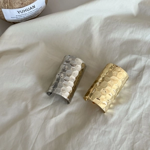 Macro shot of wide open cuff bracelets with gold and silver hammered honeycomb texture