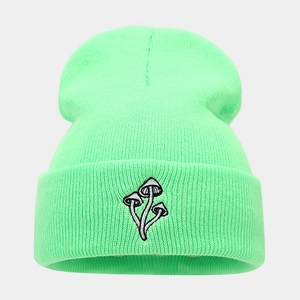 Dettaglio del berretto in maglia verde neon con ricamo di funghi sul risvolto