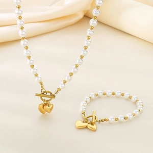 Detail of pearl jewelry set with double heart pendants and golden toggle clasps