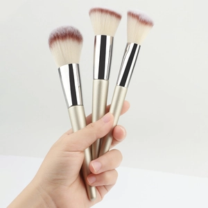 Detail of three professional makeup brushes with champagne gold handles and soft fiber bristles