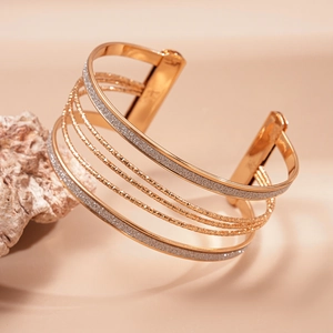 Macro shot of multi-layer rose gold open cuff bracelet with silver glitter finish