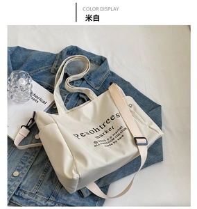 Creamy white large canvas tote bag with adjustable strap and bold black graphic text