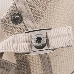 Detail of metal star-embossed snap button and mesh fabric on a beige newsboy cap