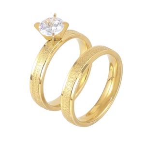 Close-up of gold-plated titanium steel couple rings with a large sparkling zircon.